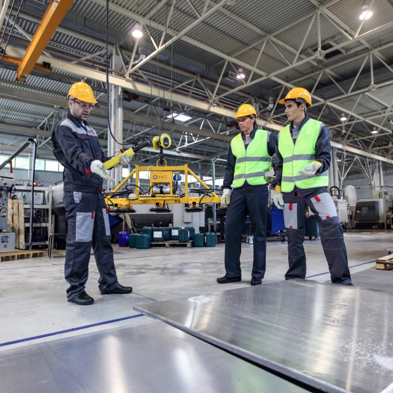 Workers standing near aluminium billets at CNC machine shop